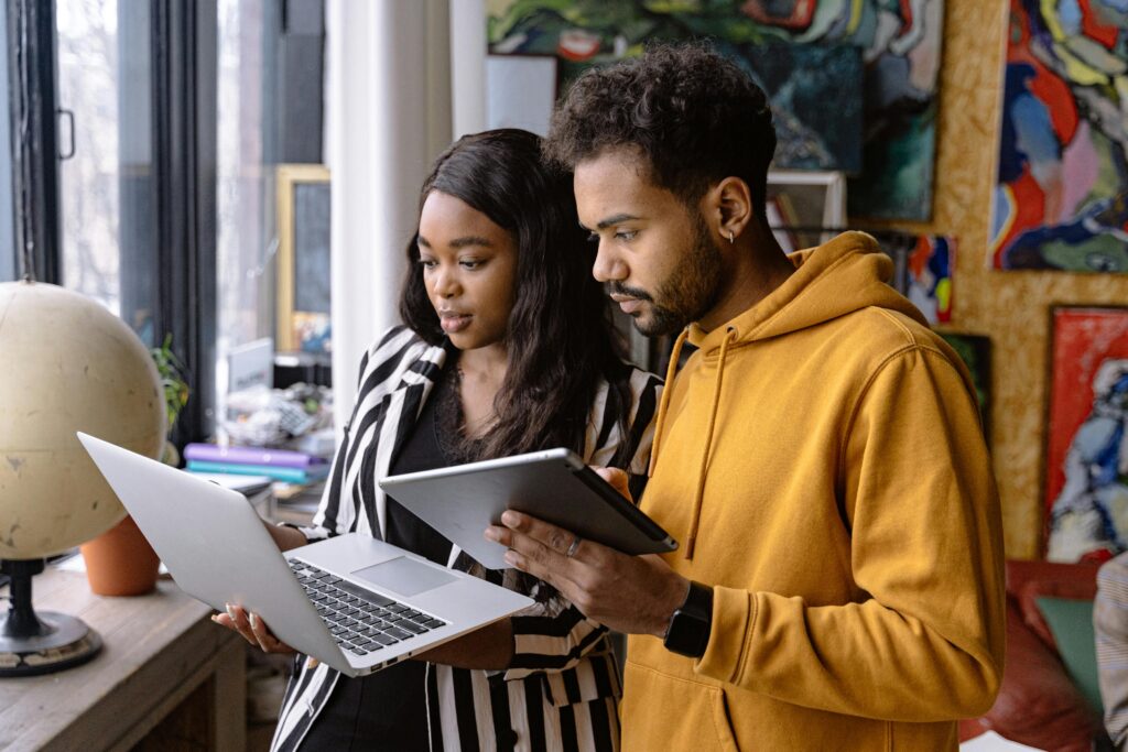 Two People Using a Laptop and a Tablet