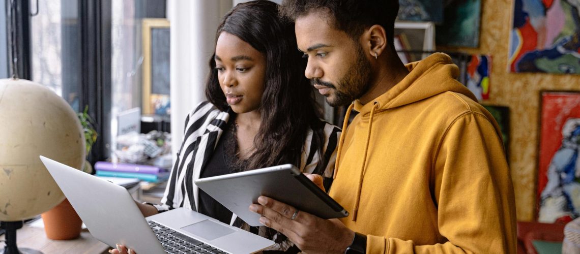 Two People Using a Laptop and a Tablet